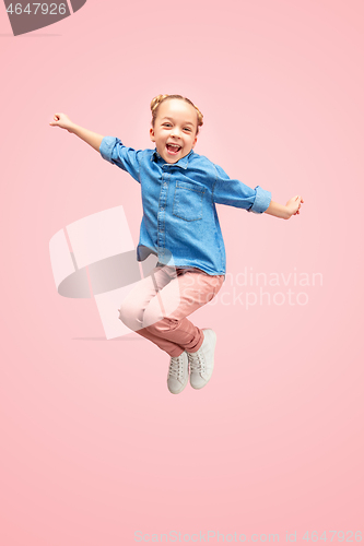 Image of Young happy caucasian teen girl jumping in the air, isolated on pink studio background.
