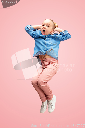 Image of Young happy caucasian teen girl jumping in the air, isolated on pink studio background.