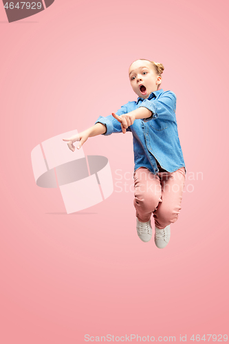 Image of Young happy caucasian teen girl jumping in the air, isolated on pink studio background.