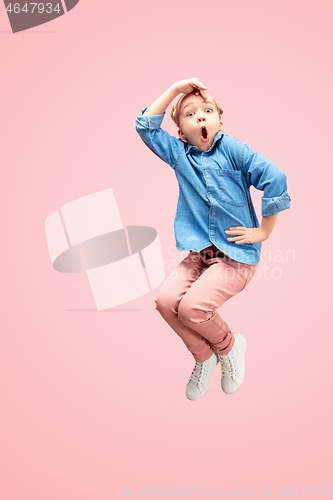Image of Young happy caucasian teen girl jumping in the air, isolated on pink studio background.