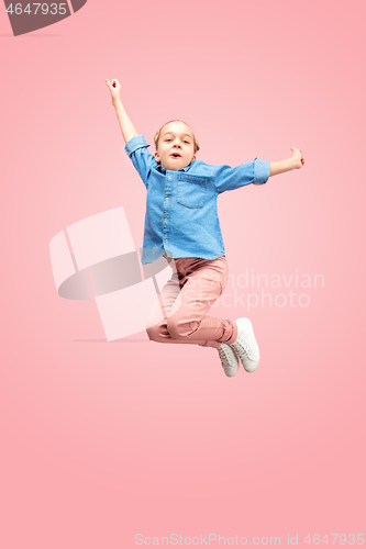 Image of Young happy caucasian teen girl jumping in the air, isolated on pink studio background.