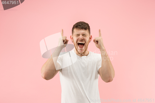 Image of The young attractive man looking suprised isolated on pink