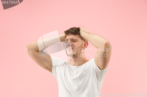 Image of Man having headache. Isolated over pink background.