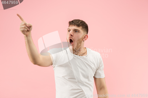 Image of The young attractive man looking suprised isolated on pink