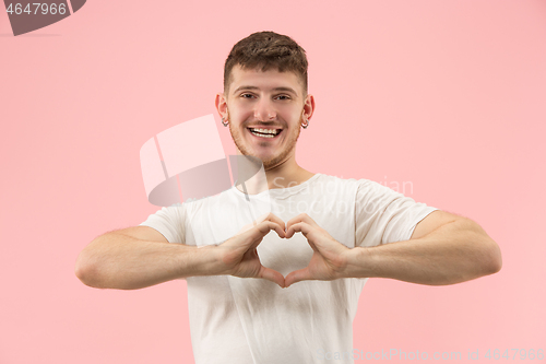 Image of Attractive guy is making a heart shape symbol with his fingers.
