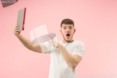 Image of portrait of smiling man pointing at laptop with blank screen isolated on white