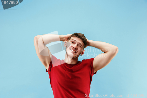 Image of The happy business man standing and smiling against blue background.