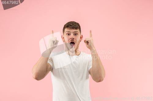 Image of The young attractive man looking suprised isolated on pink