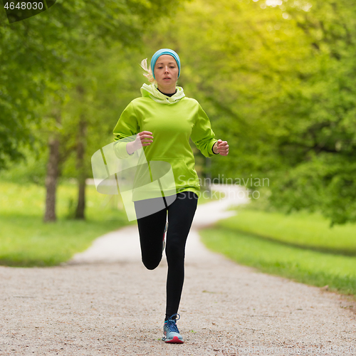 Image of Sporty young female runner in city park..