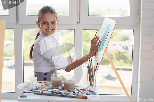 Image of Girl with a beautiful smile looks into the frame sitting behind 