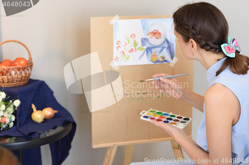 Image of Girl paints watercolor still life with nature