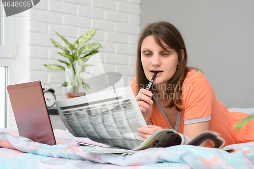 Image of A girl looks in the newspaper job ads