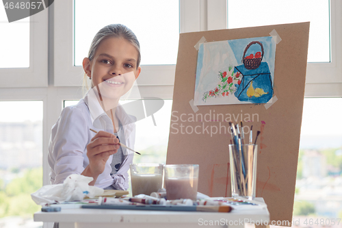 Image of Smiling girl sits at work in the studio with a brush in her hand