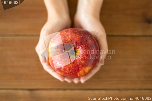 Image of close up of hands holding ripe red apple