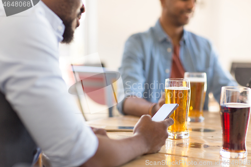 Image of man with smartphone drinking beer at bar or pub