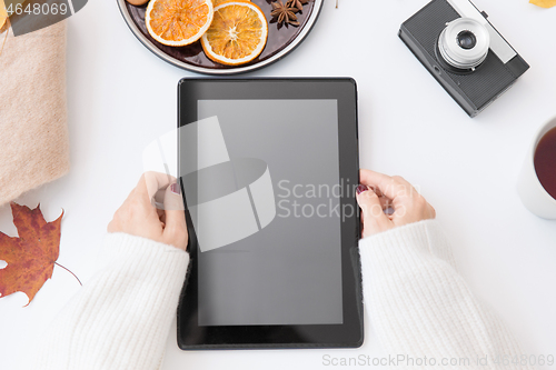 Image of hands with tablet pc, tea and autumn leaves