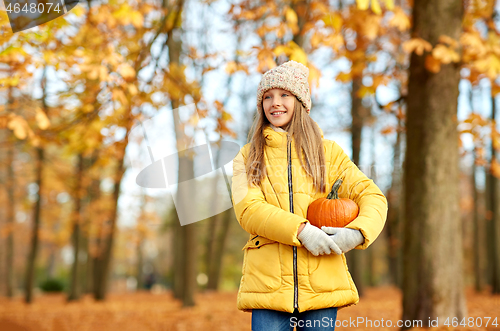 Image of happy girl with pumpkin at autumn park