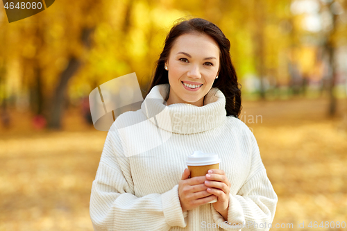 Image of woman drinking takeaway coffee in autumn park