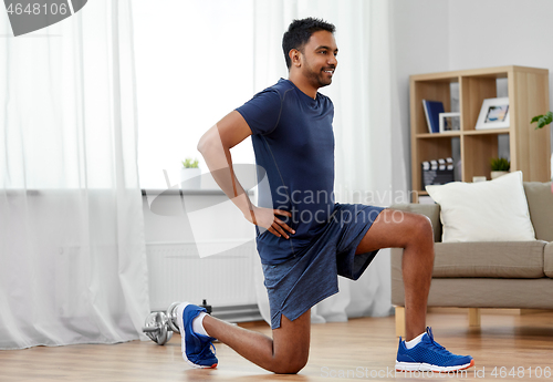 Image of indian man exercising and doing squats at home