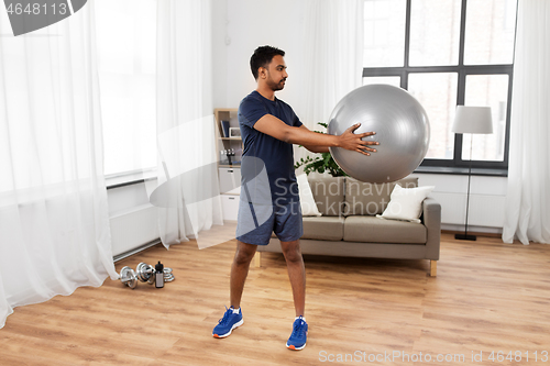 Image of indian man exercising with fitness ball at home