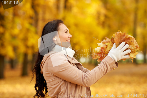 Image of happy woman having fun with leaves in autumn park