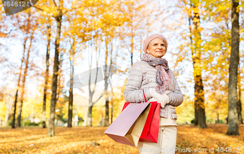 Image of senior woman with shopping bags at autumn park