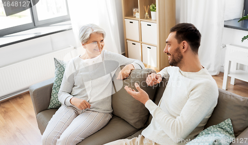 Image of senior mother talking to adult son at home