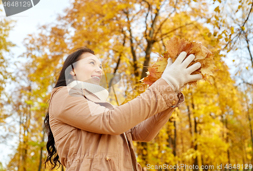 Image of happy woman having fun with leaves in autumn park