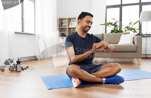 Image of smiling indian man with fitness tracker at home