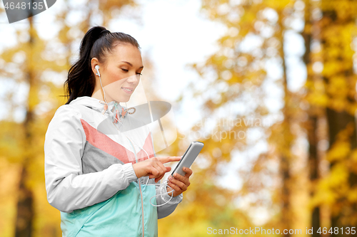 Image of woman in autumn park and listening to music