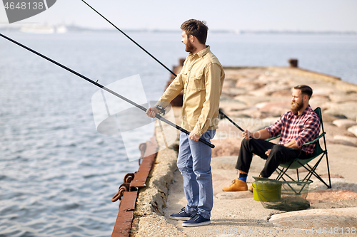 Image of happy friends with fishing rods on pier