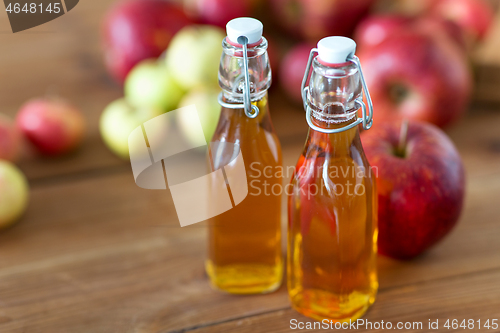 Image of bottles of apple juice or vinegar on wooden table