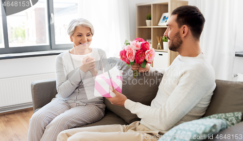 Image of son giving present and flowers to senior mother