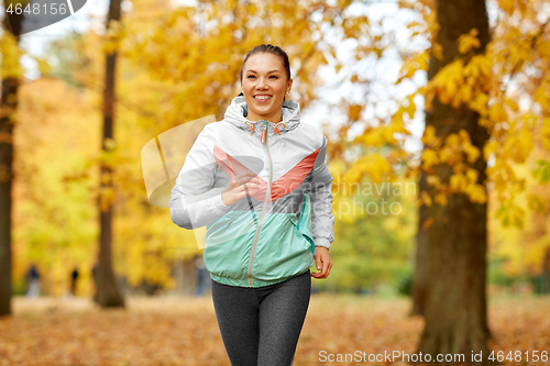 Image of young woman running in autumn park