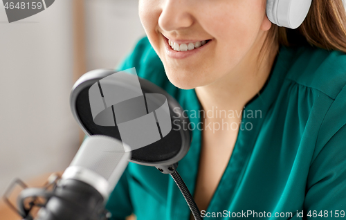 Image of woman with microphone recording podcast at studio