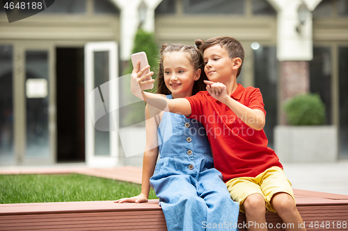 Image of Two smiling kids, boy and girl taking selfie together in town, city in summer day