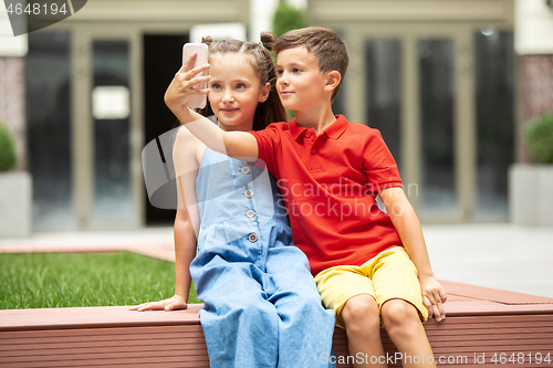 Image of Two smiling kids, boy and girl taking selfie together in town, city in summer day
