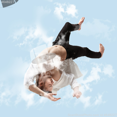 Image of Mid-air beauty. Full length studio shot of attractive young man hovering in air and keeping eyes closed