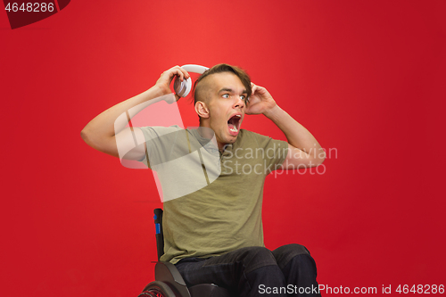 Image of Caucasian young man\'s portrait isolated on red studio background. Human emotions concept