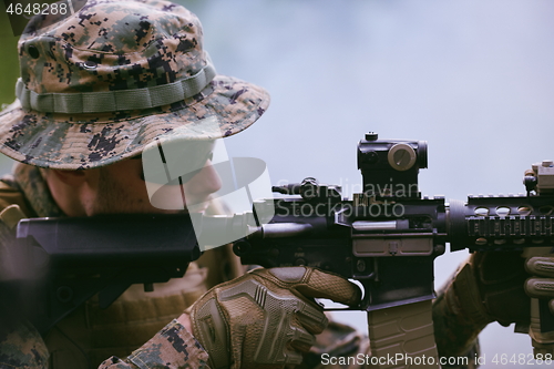 Image of soldier in action aiming  on weapon  laser sight optics