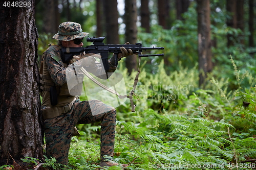 Image of soldier in action aiming  on weapon  laser sight optics