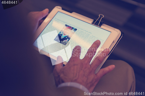 Image of Closeup of mature hands holding tablet.