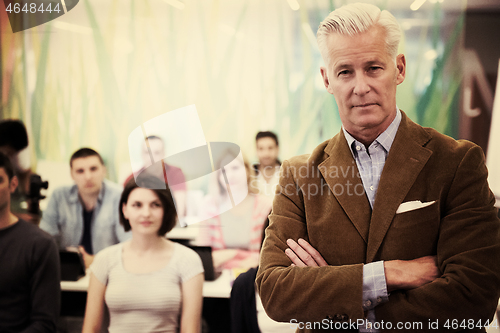 Image of portrait of  teacher with students group in background