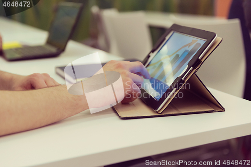 Image of Closeup of mature hands holding tablet.