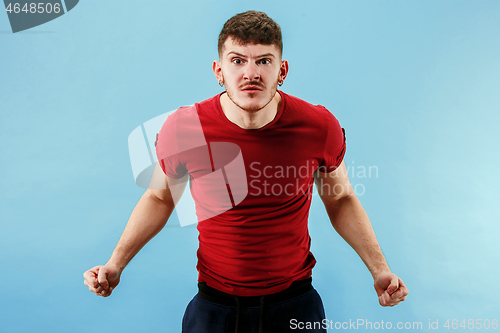 Image of The young emotional angry man screaming on blue studio background