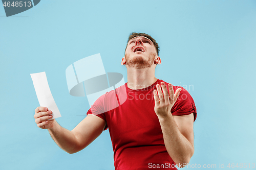 Image of Young boy with a surprised expression bet slip on blue background