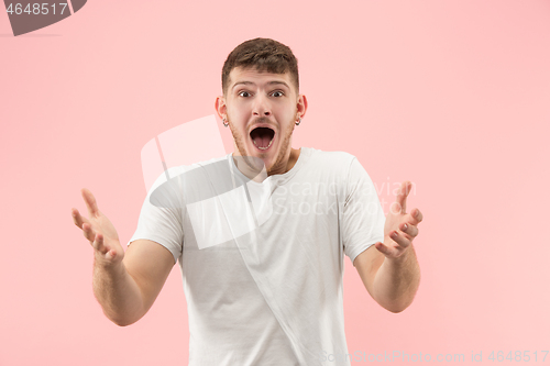 Image of The young attractive man looking suprised isolated on pink