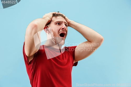 Image of The young emotional angry man screaming on blue studio background