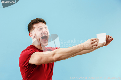 Image of Young boy with a surprised expression bet slip on blue background