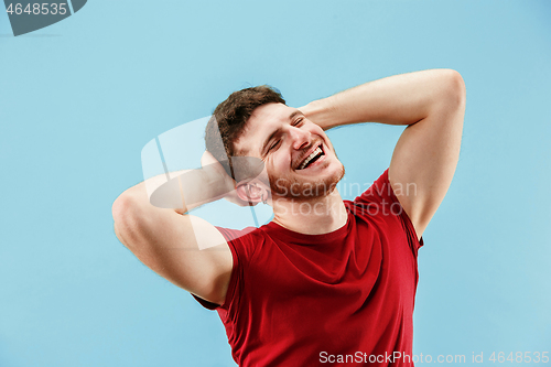 Image of The happy business man standing and smiling against blue background.